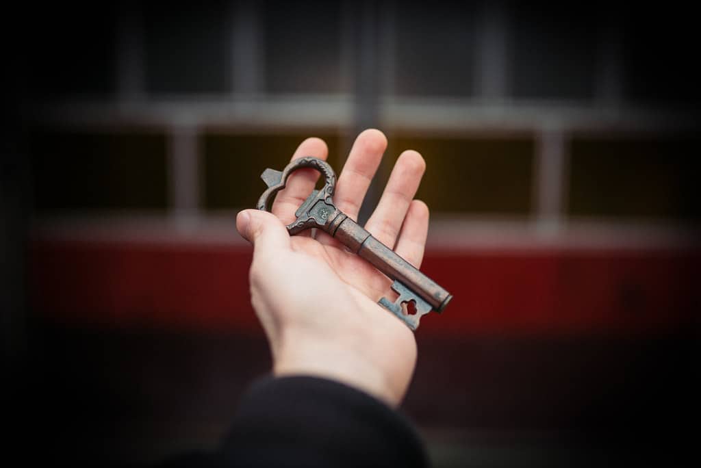 Hand holding a key in front of an apartment door, ready for check-in