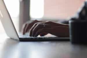 Close-up of hands typing on a laptop keyboard while booking a stay online