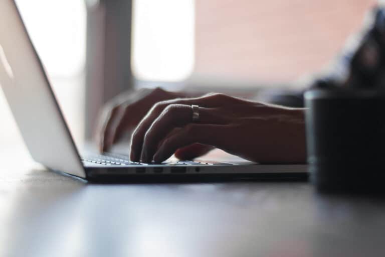 Close-up of hands typing on a laptop keyboard while booking a stay online